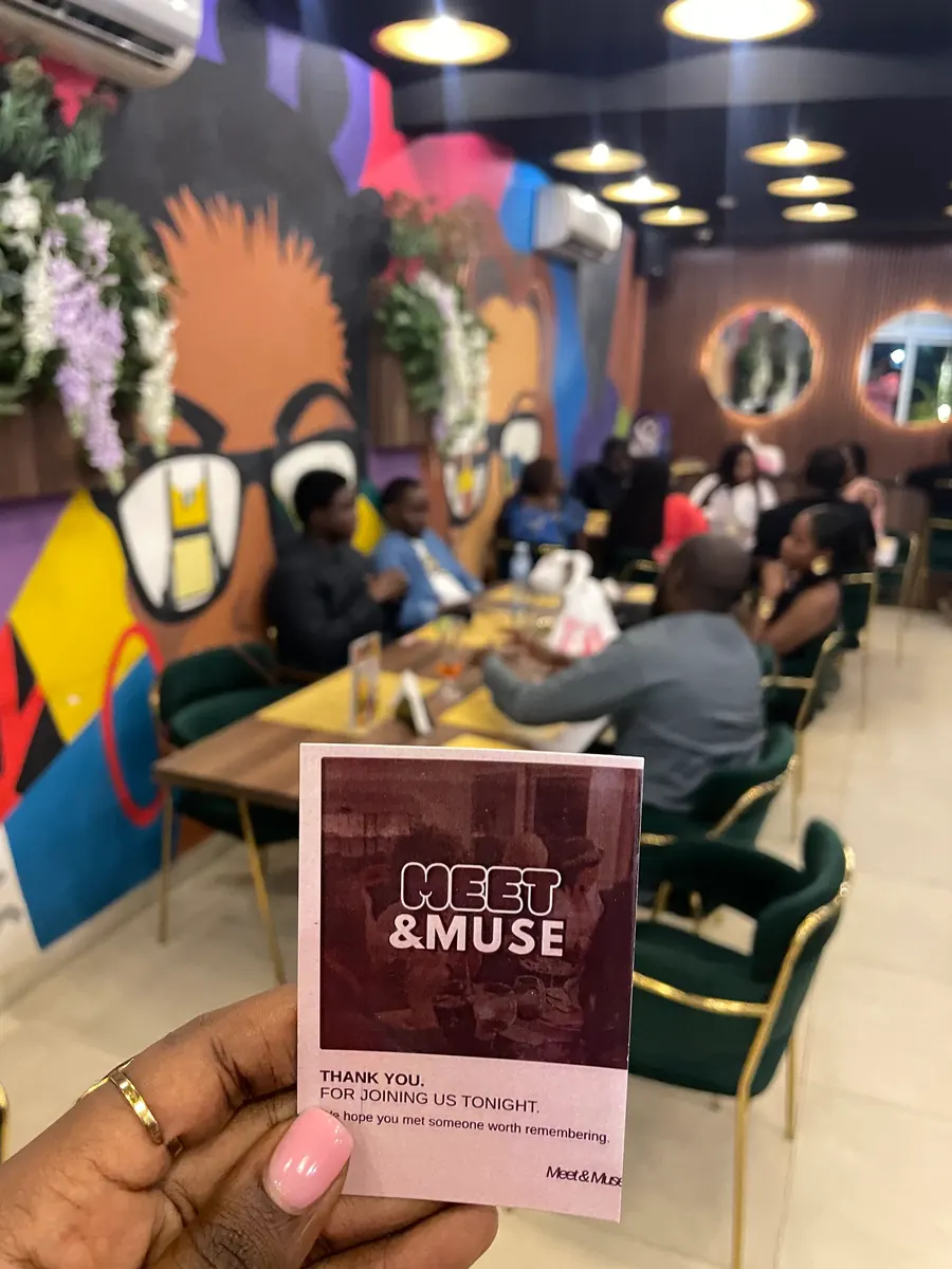 A Meet & Muse thank-you card held up at the restaurant